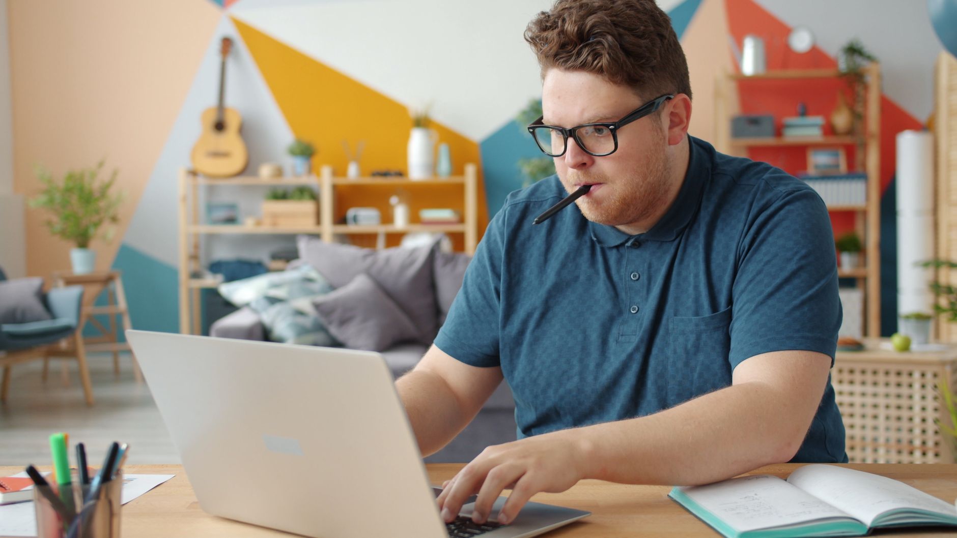 Jeune professionnel concentré, travaillant sur un ordinateur portable dans un bureau à domicile élégant.