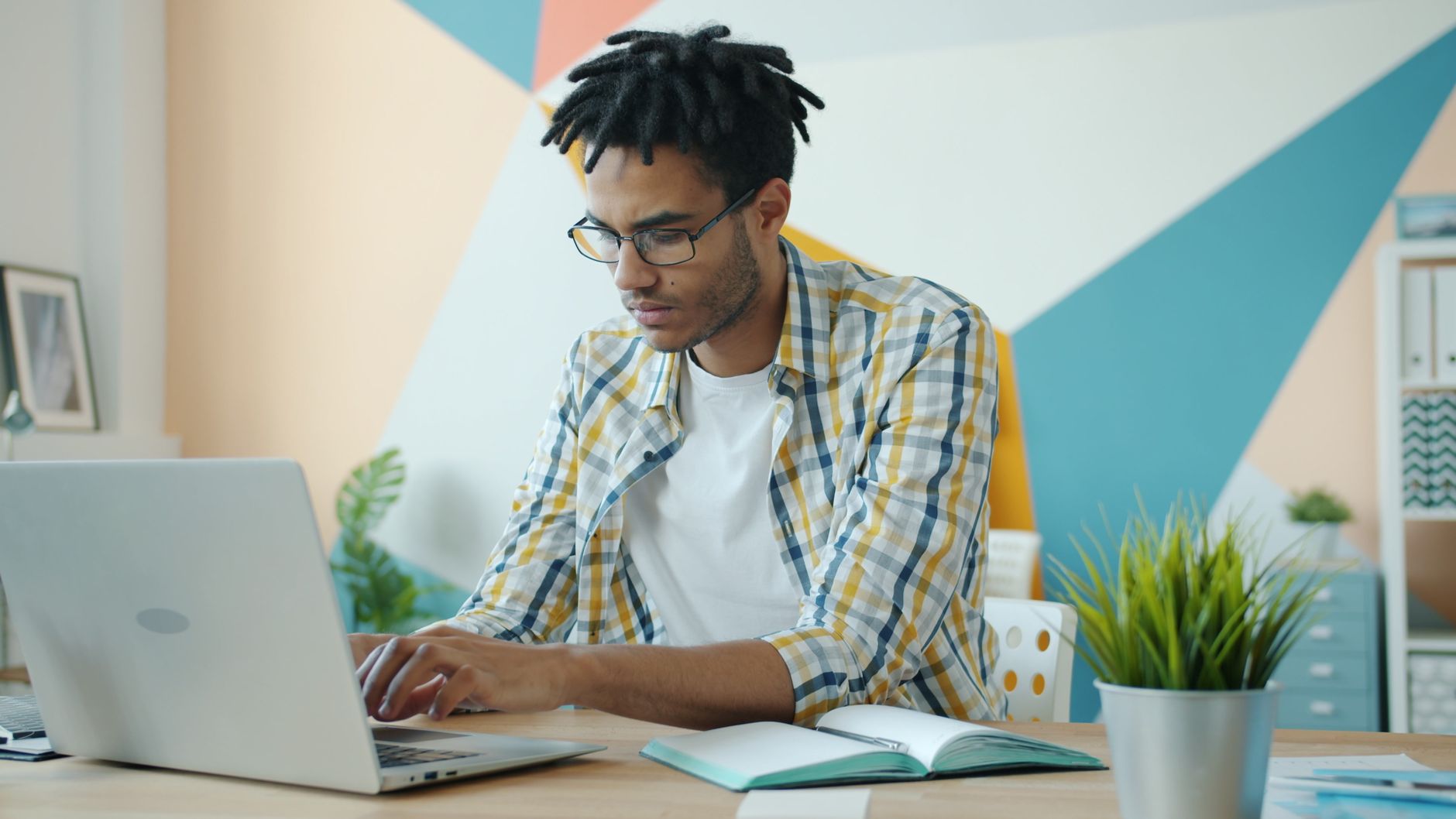 Jeune professionnel travaillant sur un ordinateur portable dans un bureau moderne, concentré et productif.