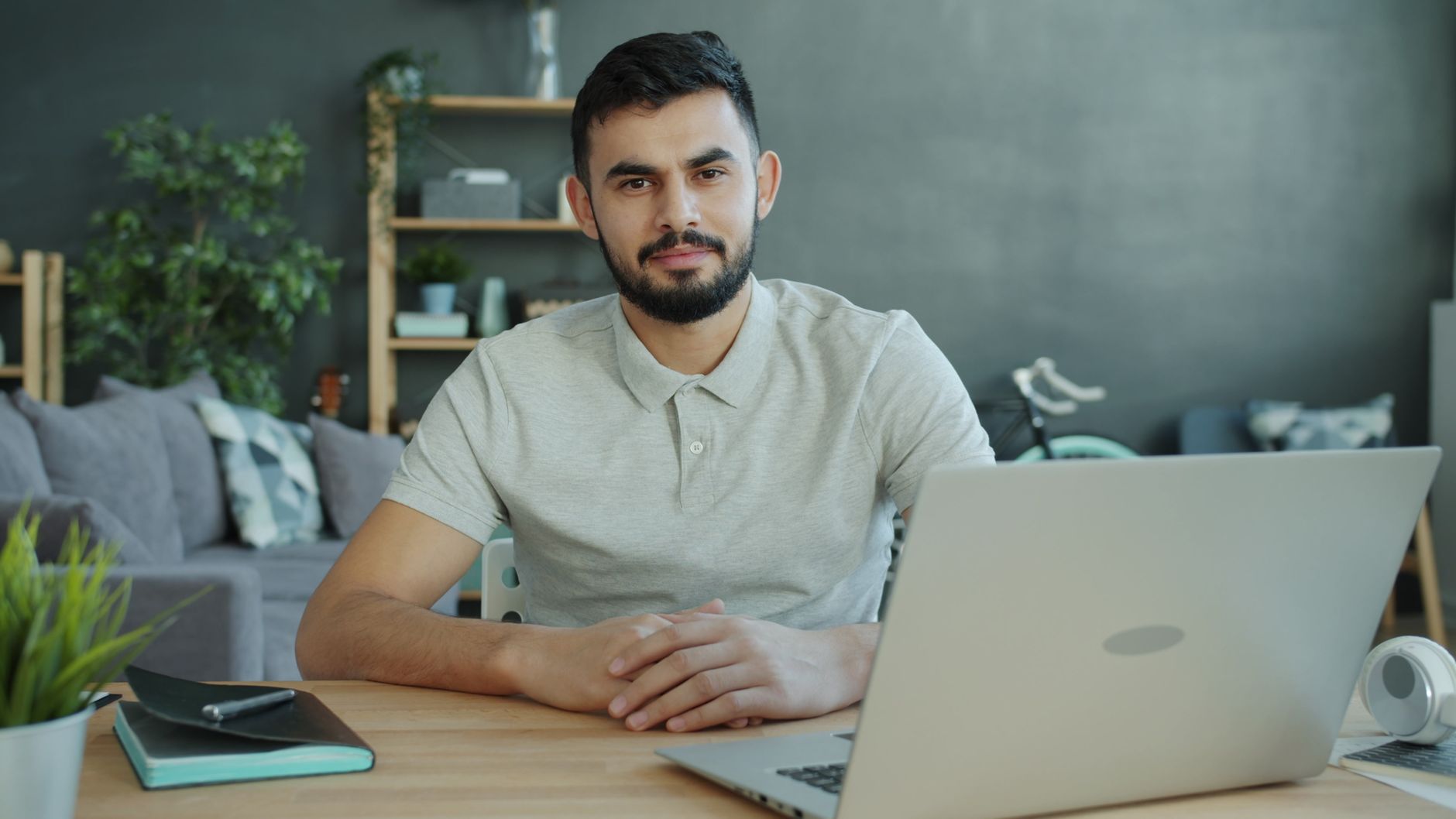 Jeune homme assis dans un bureau à domicile moderne, travaillant sur un ordinateur portable.
